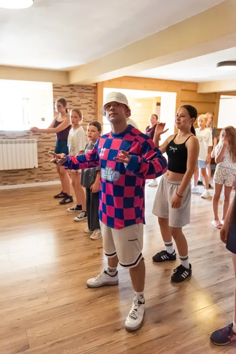 Cała grupa ćwiczy choreografię na sali tanecznej podczas warsztatów