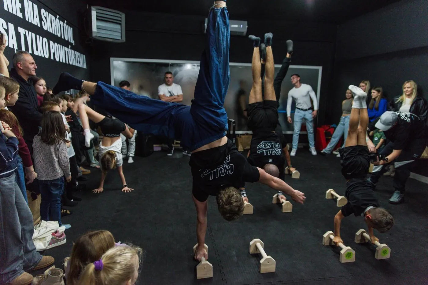 Grupa ćwicząca handstand na poręczach